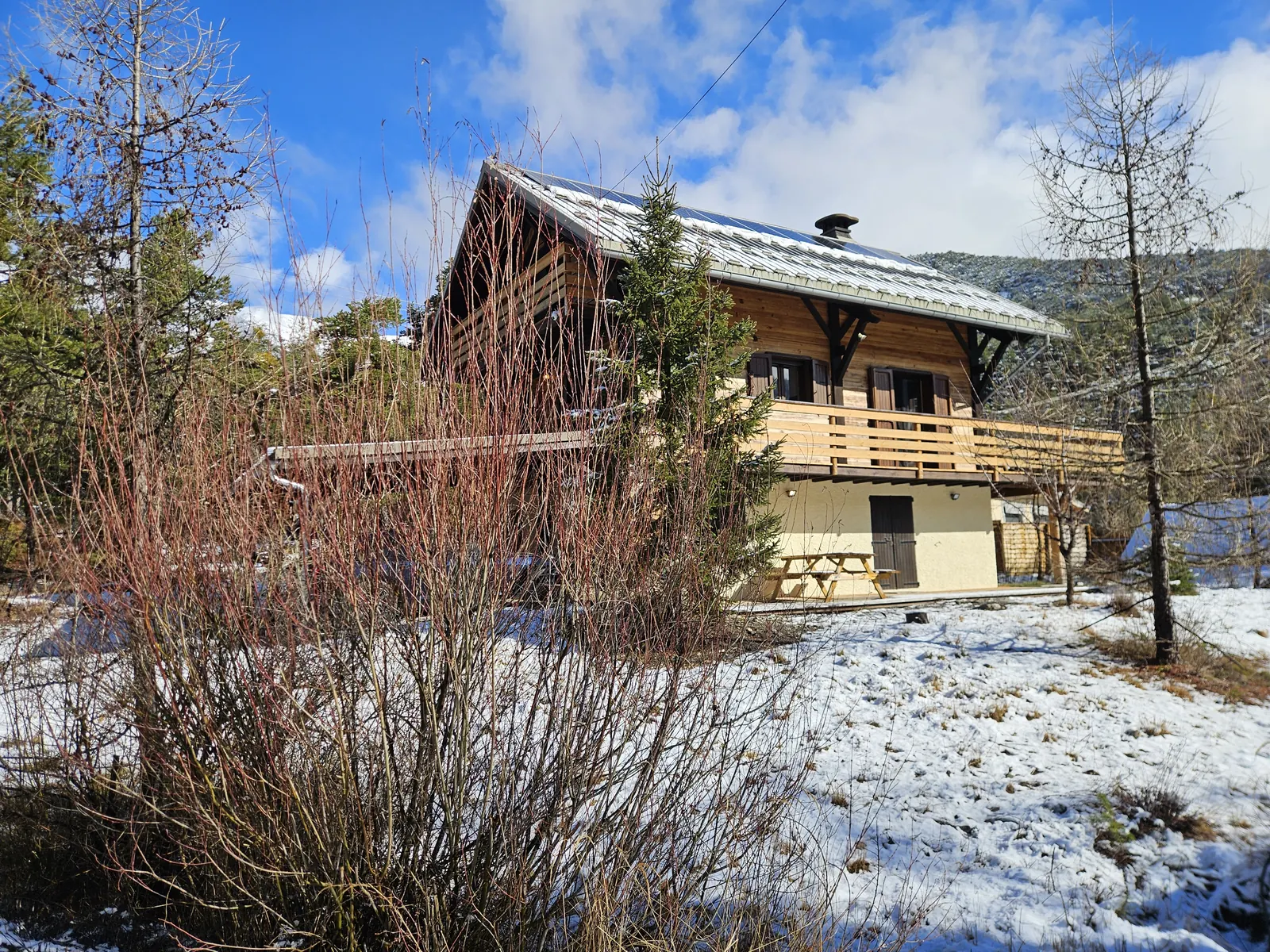 Le chalet en bois du Petit Torrent, sa terrasse et les montagnes enneigées