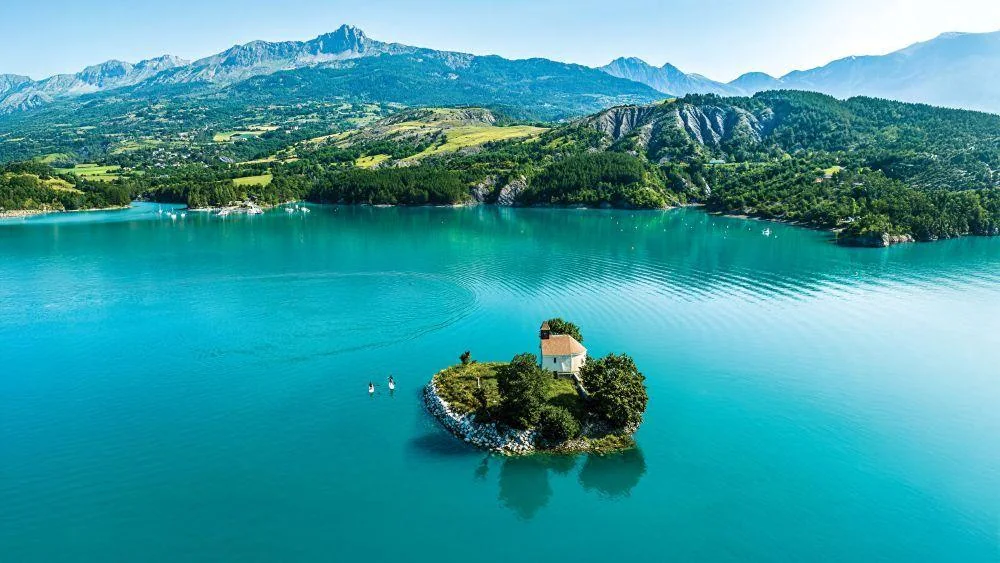 Vue panoramique du lac de Serre-Ponçon avec la chapelle Saint-Michel sur son îlot et les montagnes des Alpes du Sud